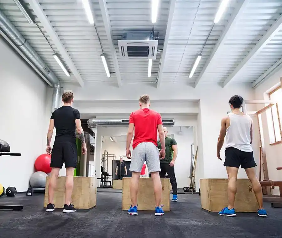 Men in gym with trainer exercising on fit